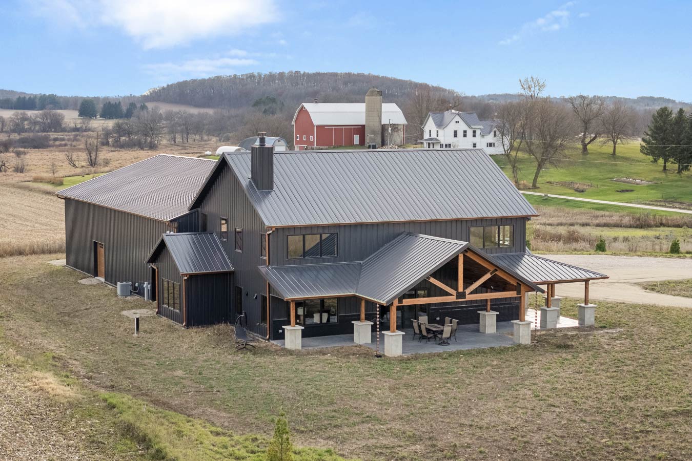 This breathtaking barndominium features cedar trusses and a wraparound porch, blending rustic charm with modern design in the countryside.