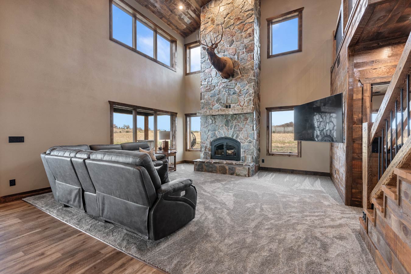 This family room offers plush seating, a grand fireplace, and large windows that bring the outdoors in.