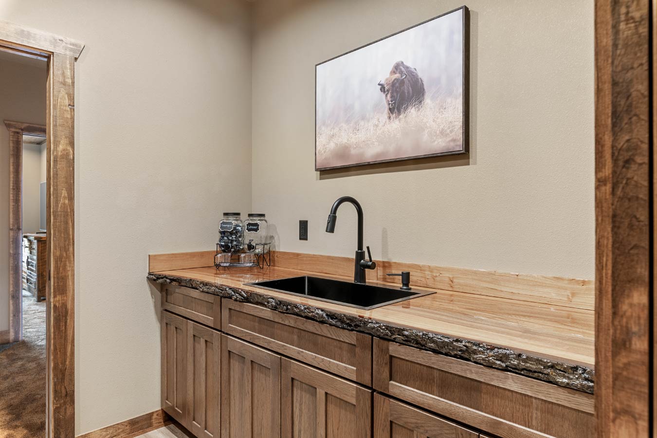 A rustic kitchenette in the Barndominium with Workshop, featuring a live-edge countertop and modern black fixtures.