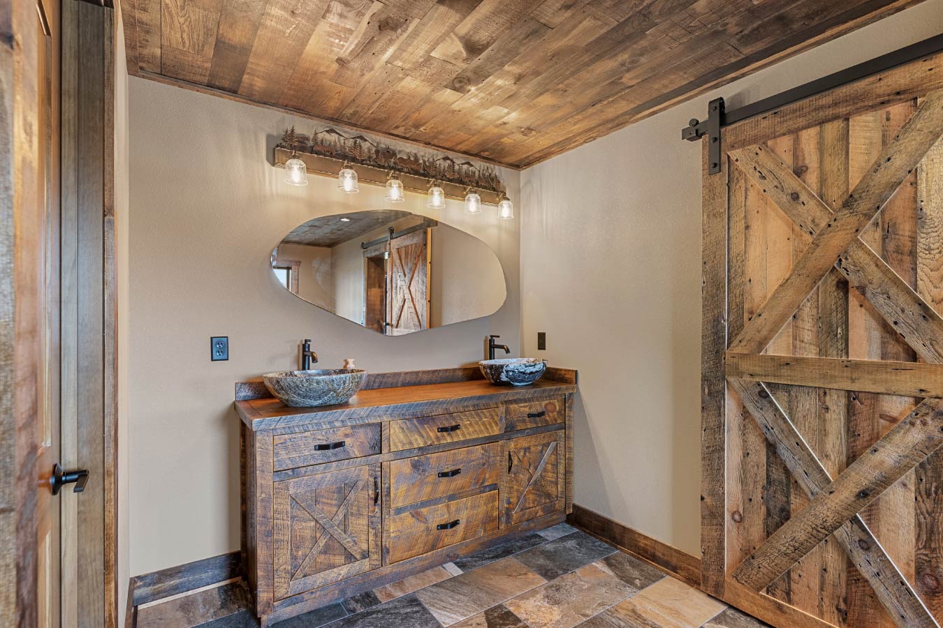 A luxurious rustic bathroom featuring a barn-style vanity and bowl sinks.
